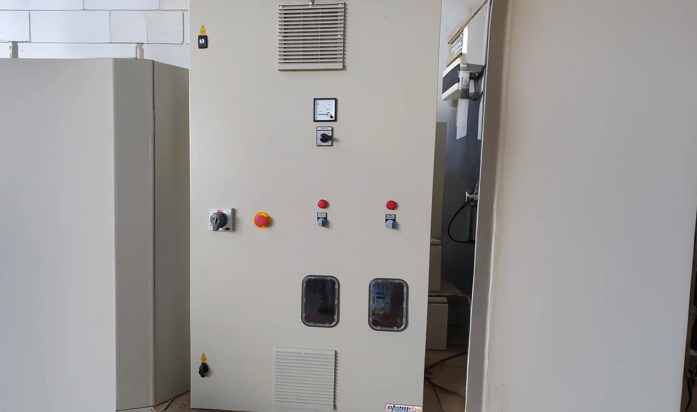 Painel elétrico industrial fechado, com botões de controle, chaves e medidor analógico na parte frontal