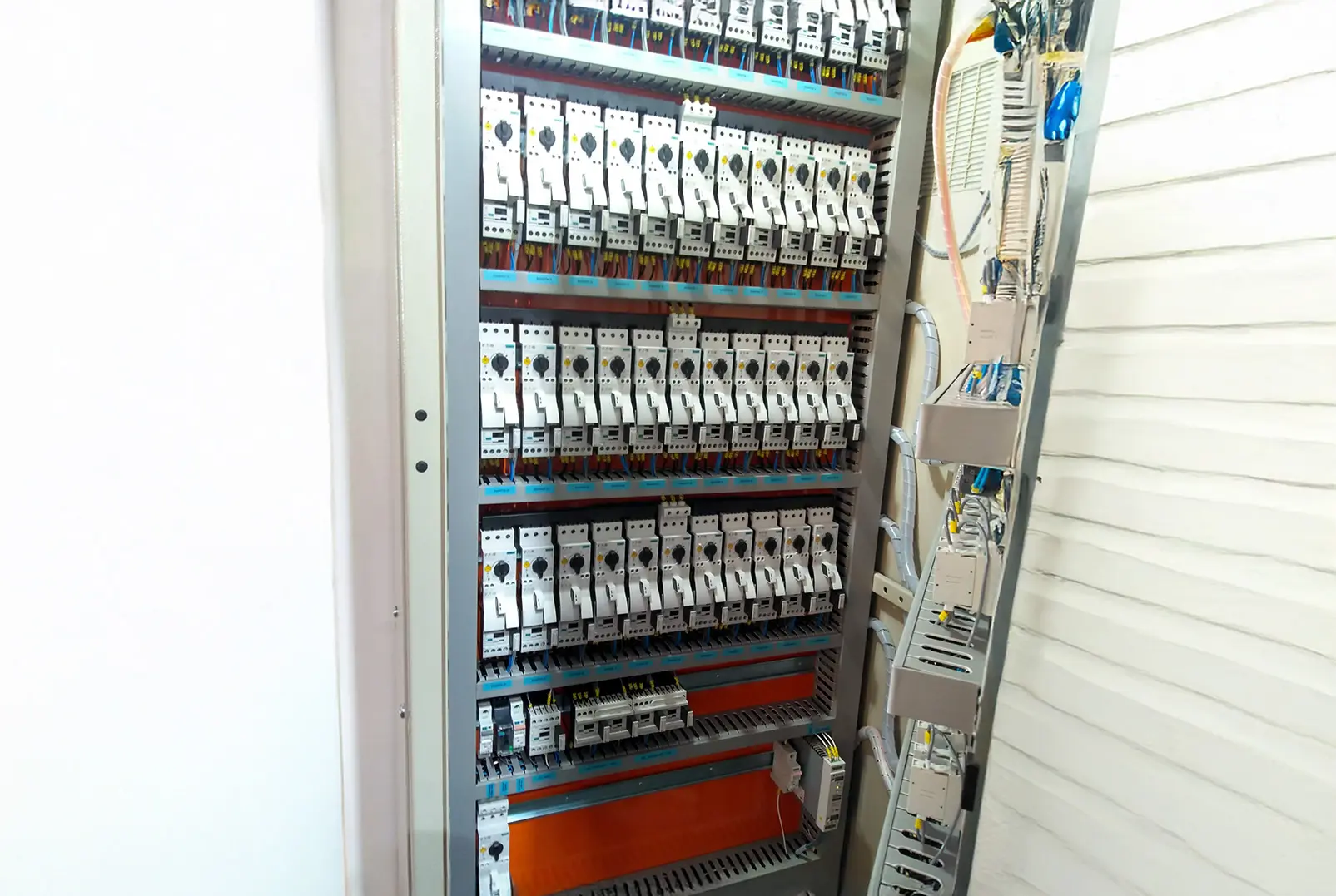 Painel de comando elétrico industrial aberto, exibindo disjuntores, componentes elétricos e organização de cabos